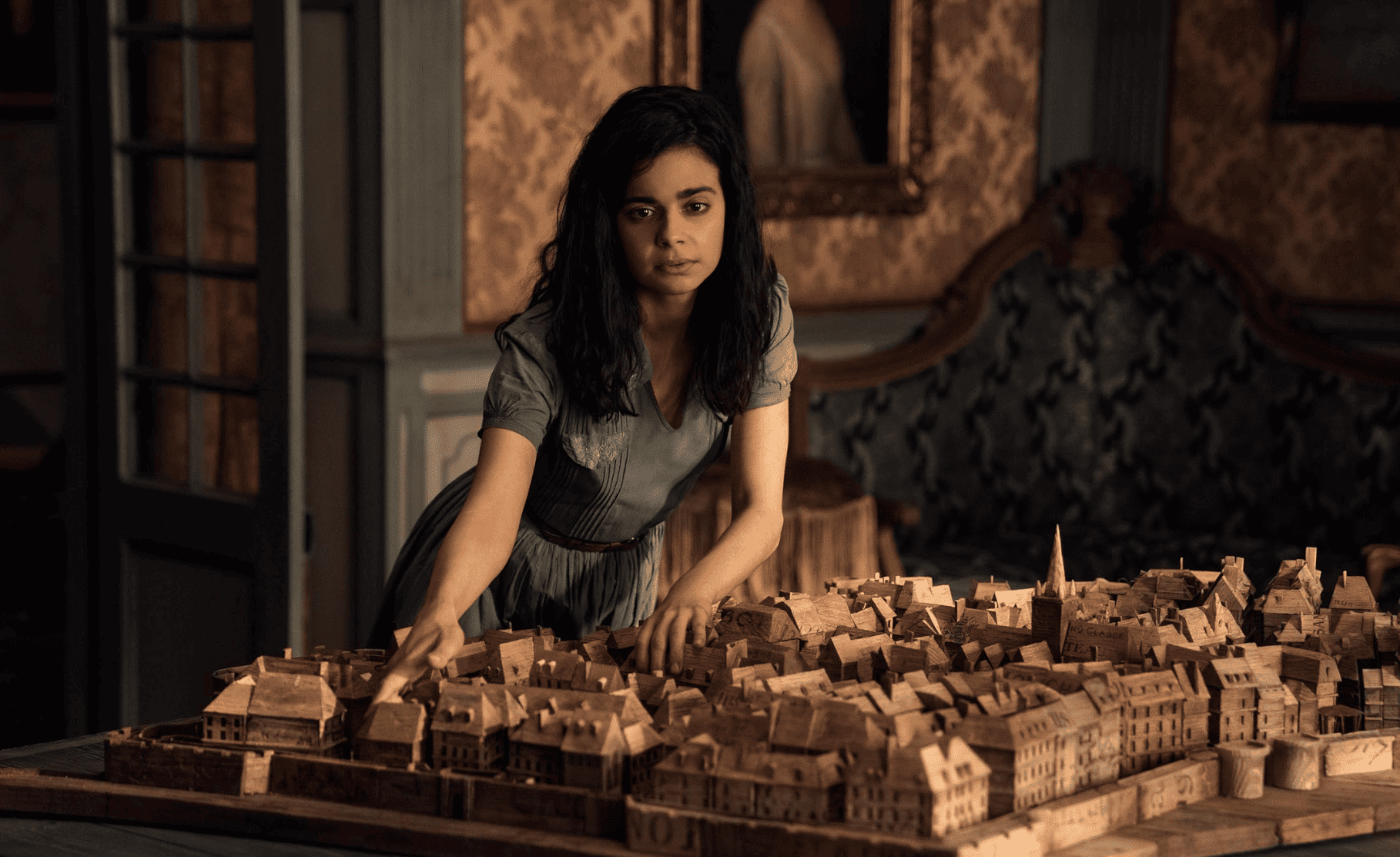 A girl studies a wooden diorama of a city in this image from 21 Laps Entertainment. 