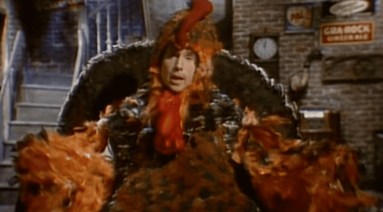 A man dressed in a turkey suit stands on stage in this image from SNL Studios.