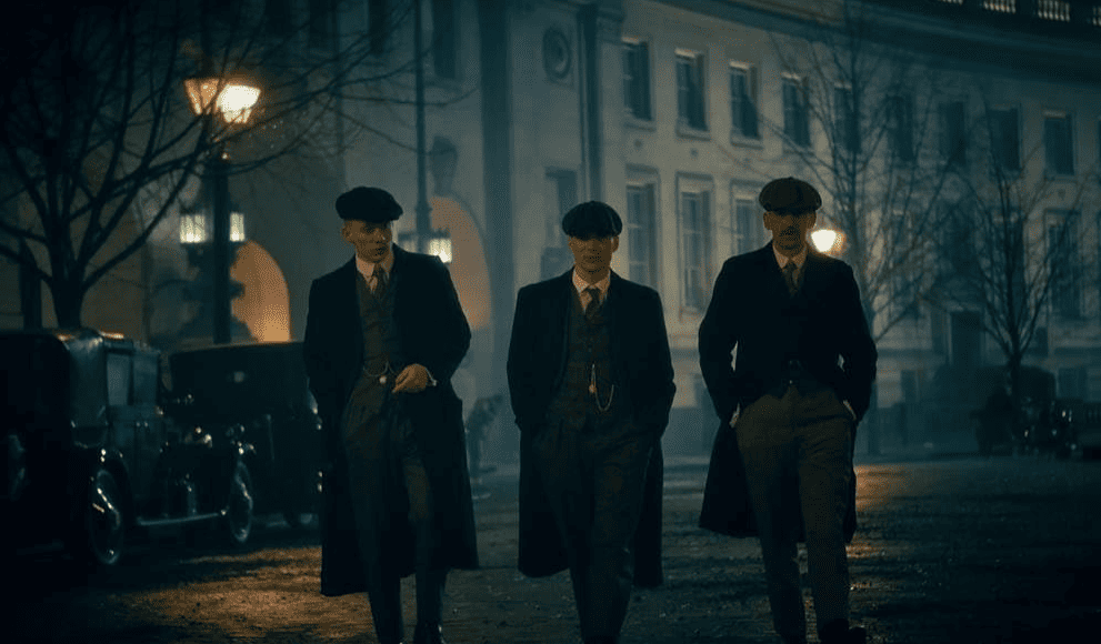 Three men in suits walk together at night in this image from Caryn Mandabach Productions. 