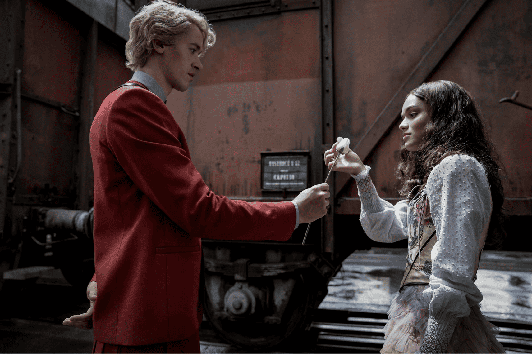 A man in a red suit gives a white rose to a girl in this image from Lionsgate Films.