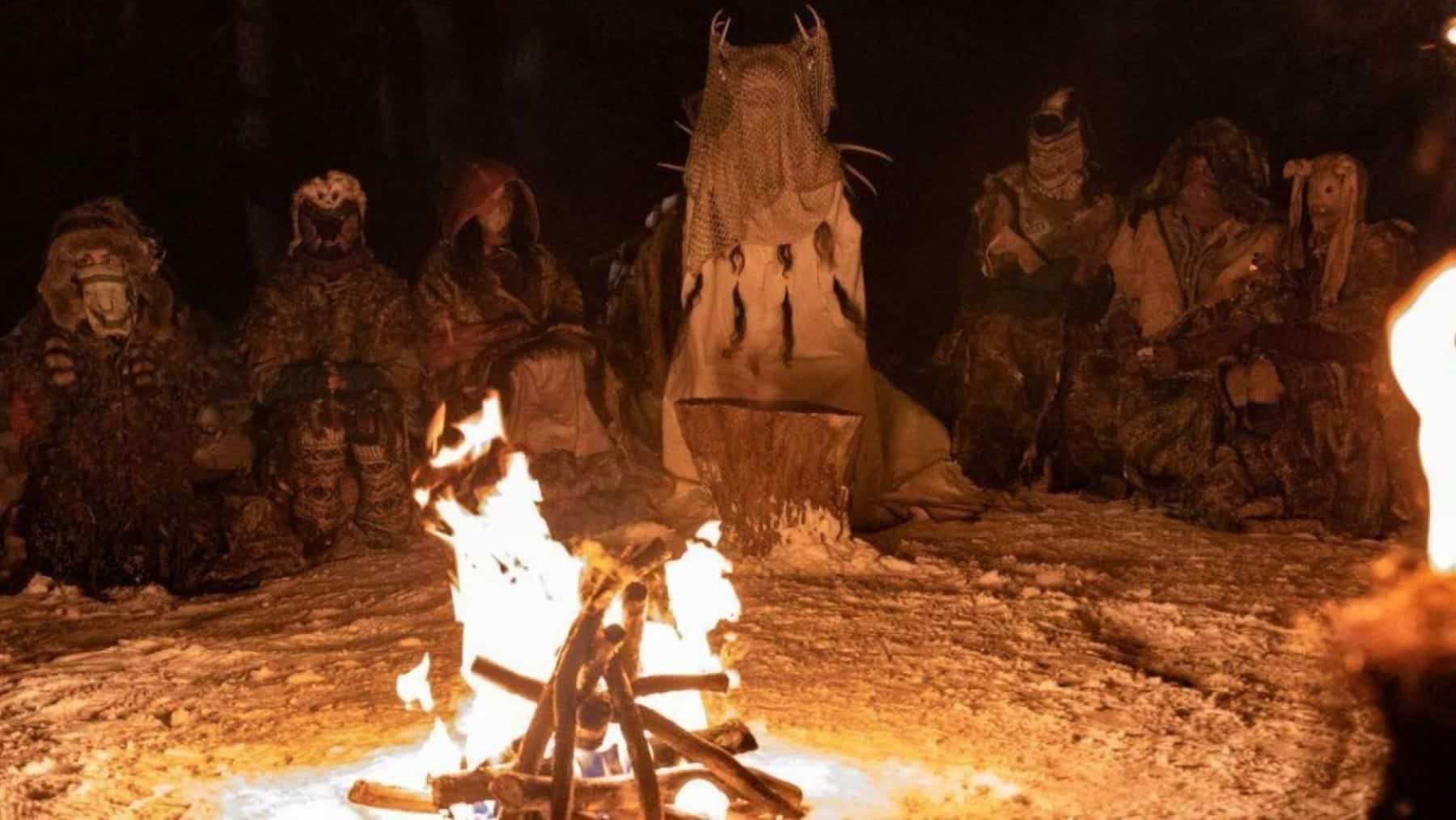 A group of masked individuals sits around a bonfire in this photo by Showtime.
