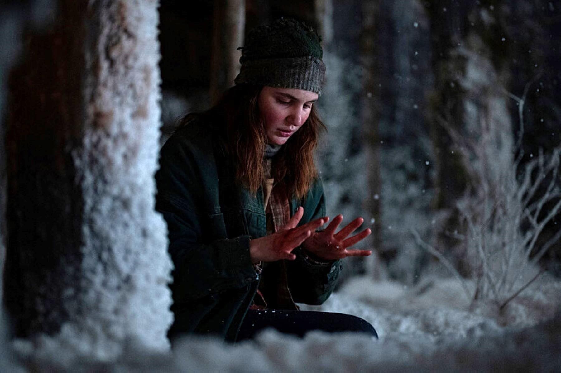 A woman examines her hands while kneeling in the snow in this photo by Showtime.