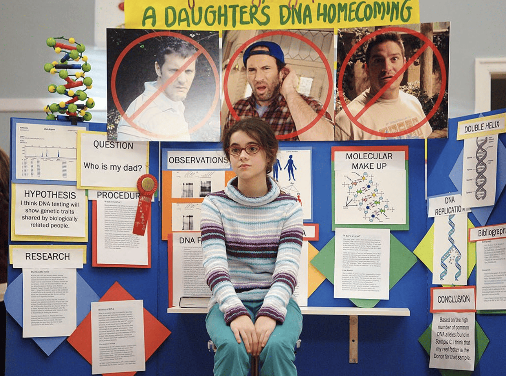 A middle school girl sits in front of her science project in this image from Warner Bros. Television.
