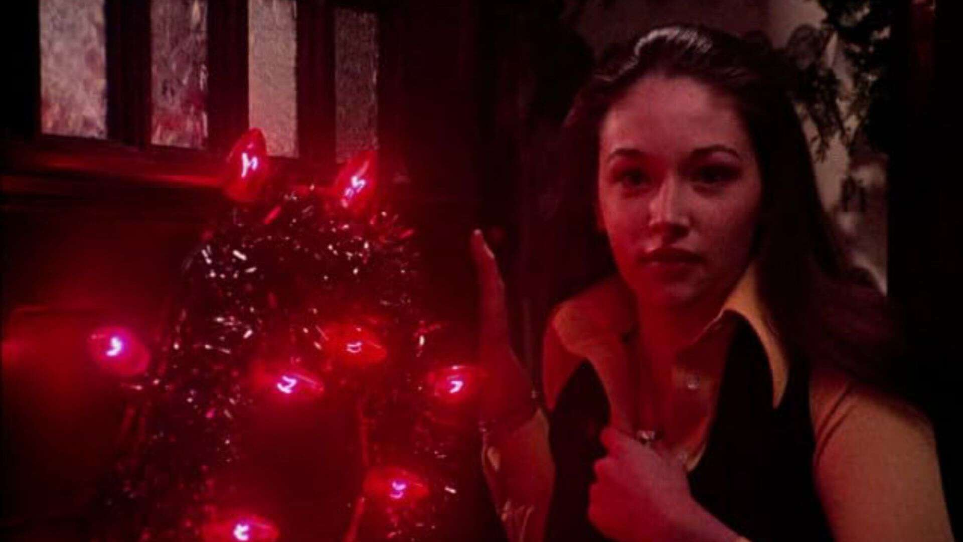  A young woman opens the front door with a wreath of red lights on it in this image from Film Funding Ltd.
