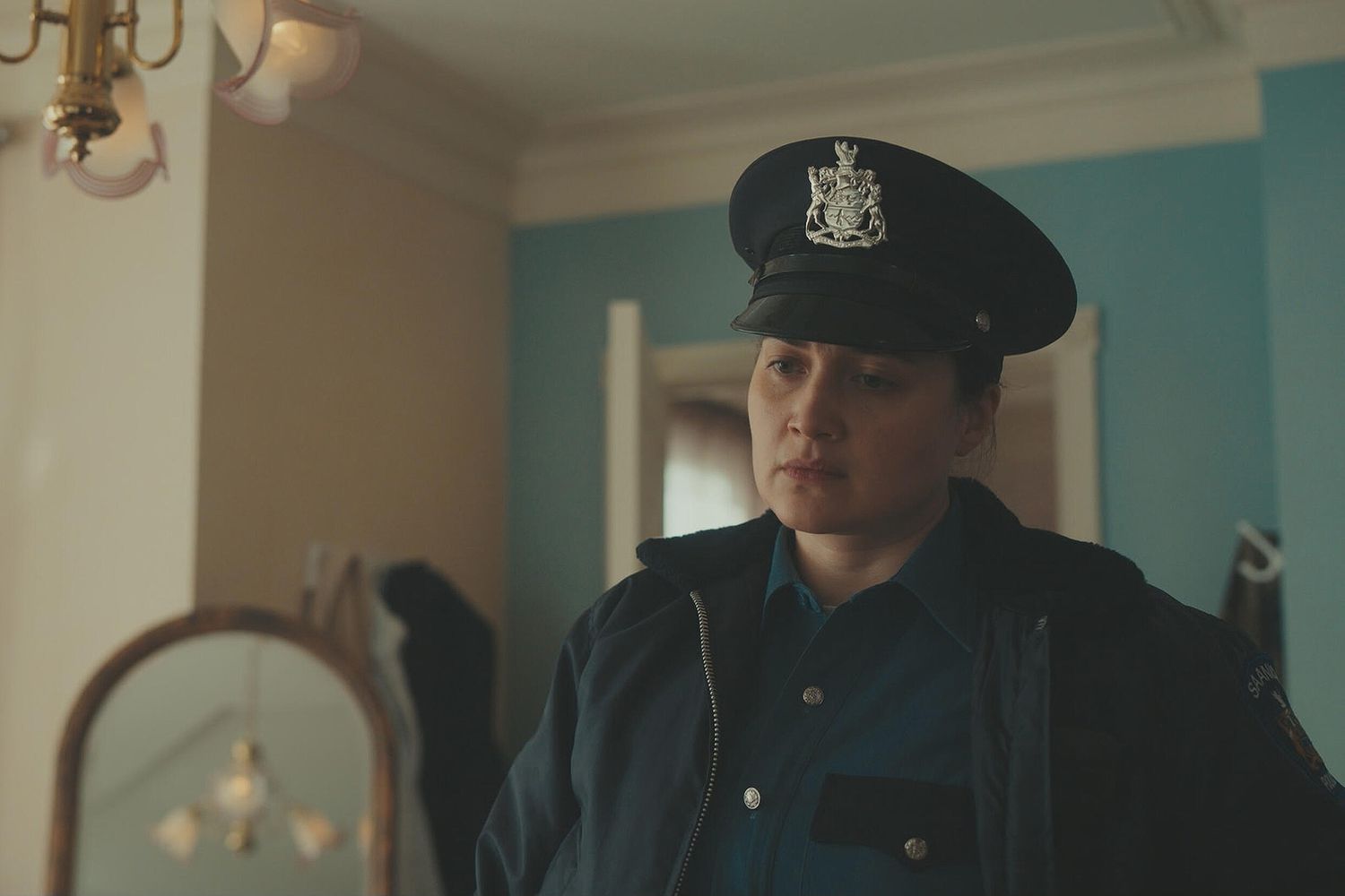 A female police officer in uniform stands inside a home in this image from Best Day Ever Productions.