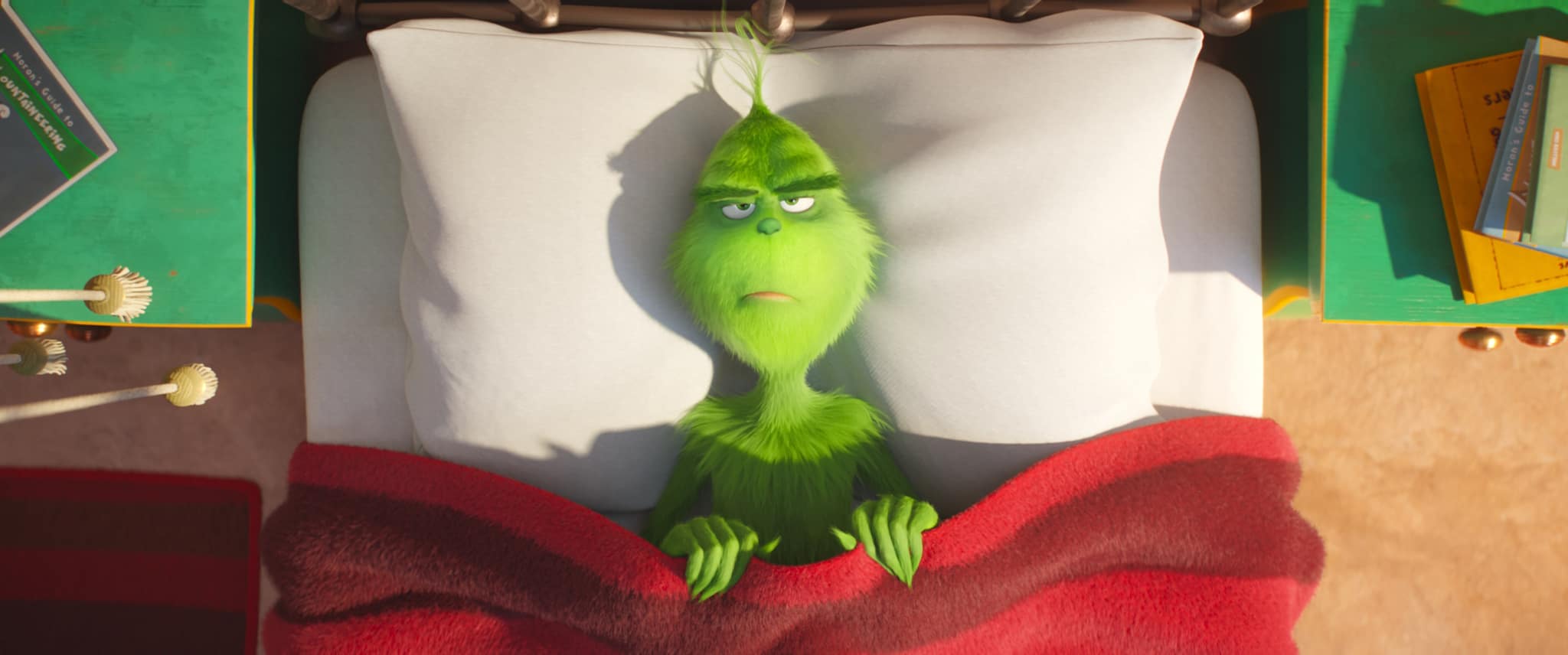 An animated Grinch in a red and green bedroom in this image from Universal Pictures.