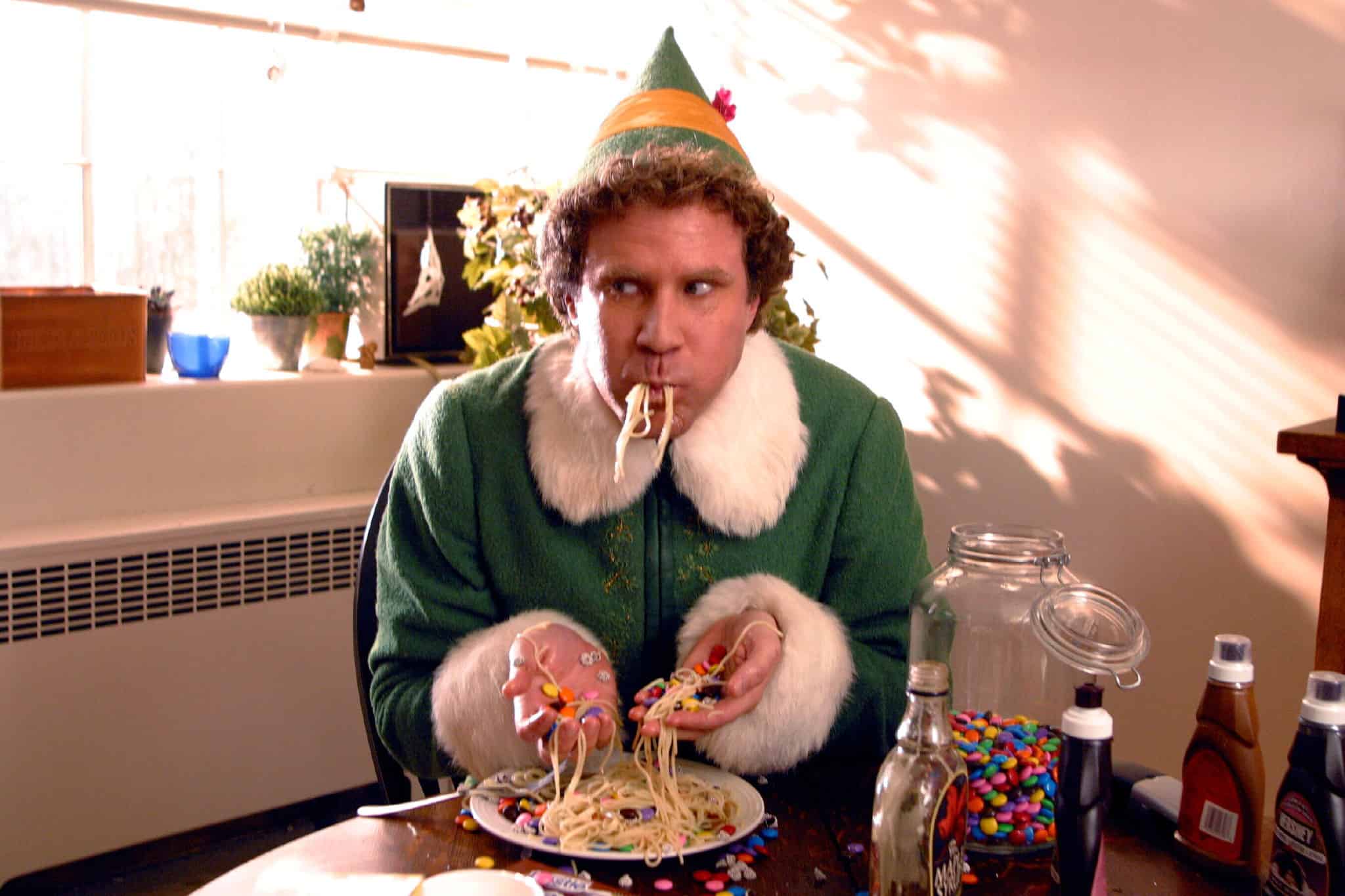 A human-sized elf eating spaghetti and M&Ms with his hands in this image from New Line Cinema.