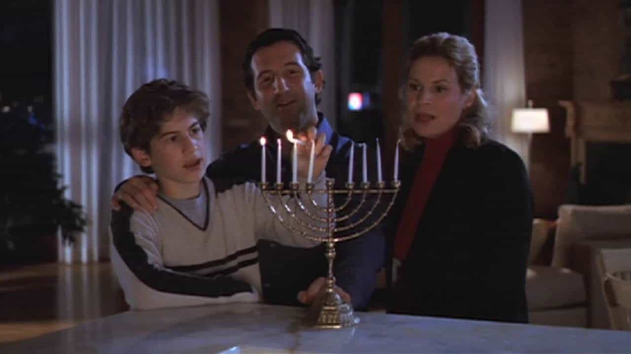A son and his parents light a menorah in this photo from Daniel L. Paulson Productions.