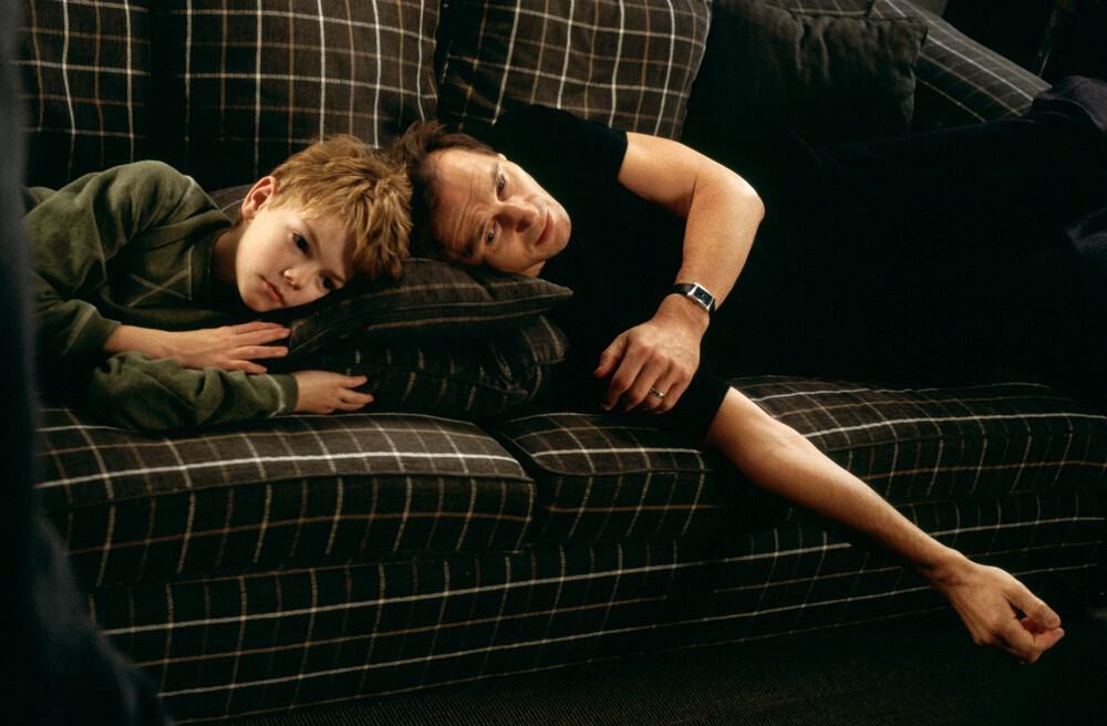 A father and stepson lie forlorn on a sofa in this image from StudioCanal.