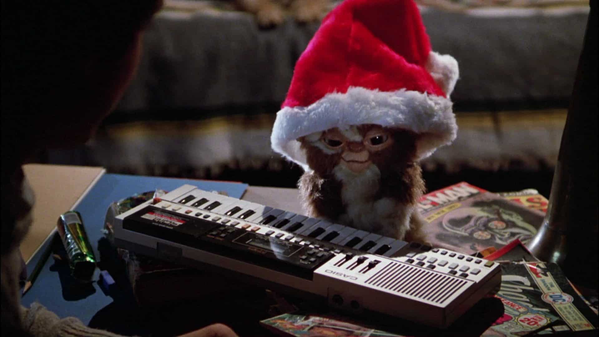 An animatronic gremlin in a Santa hat at a keyboard in this image from Warner Bros.