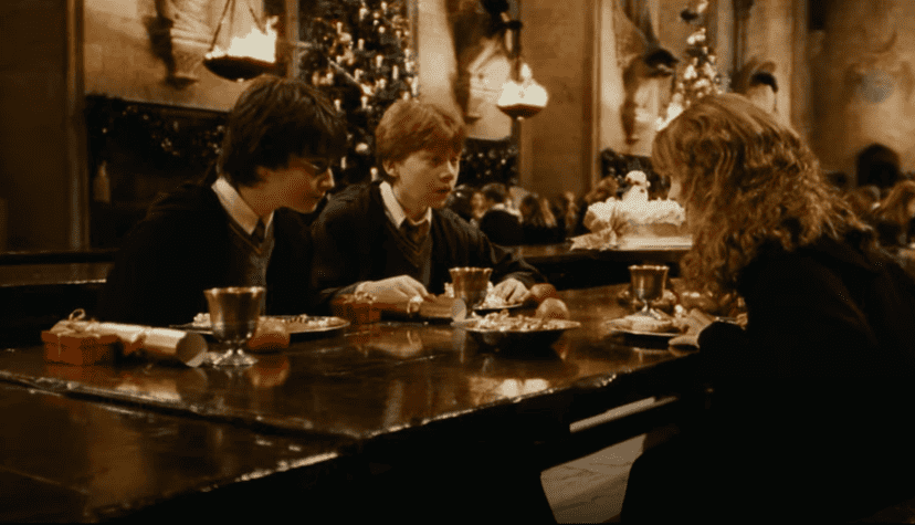 Two boys and a girl sit on opposite sides of a table during a Christmas meal in this image from Warner Bros. Pictures.