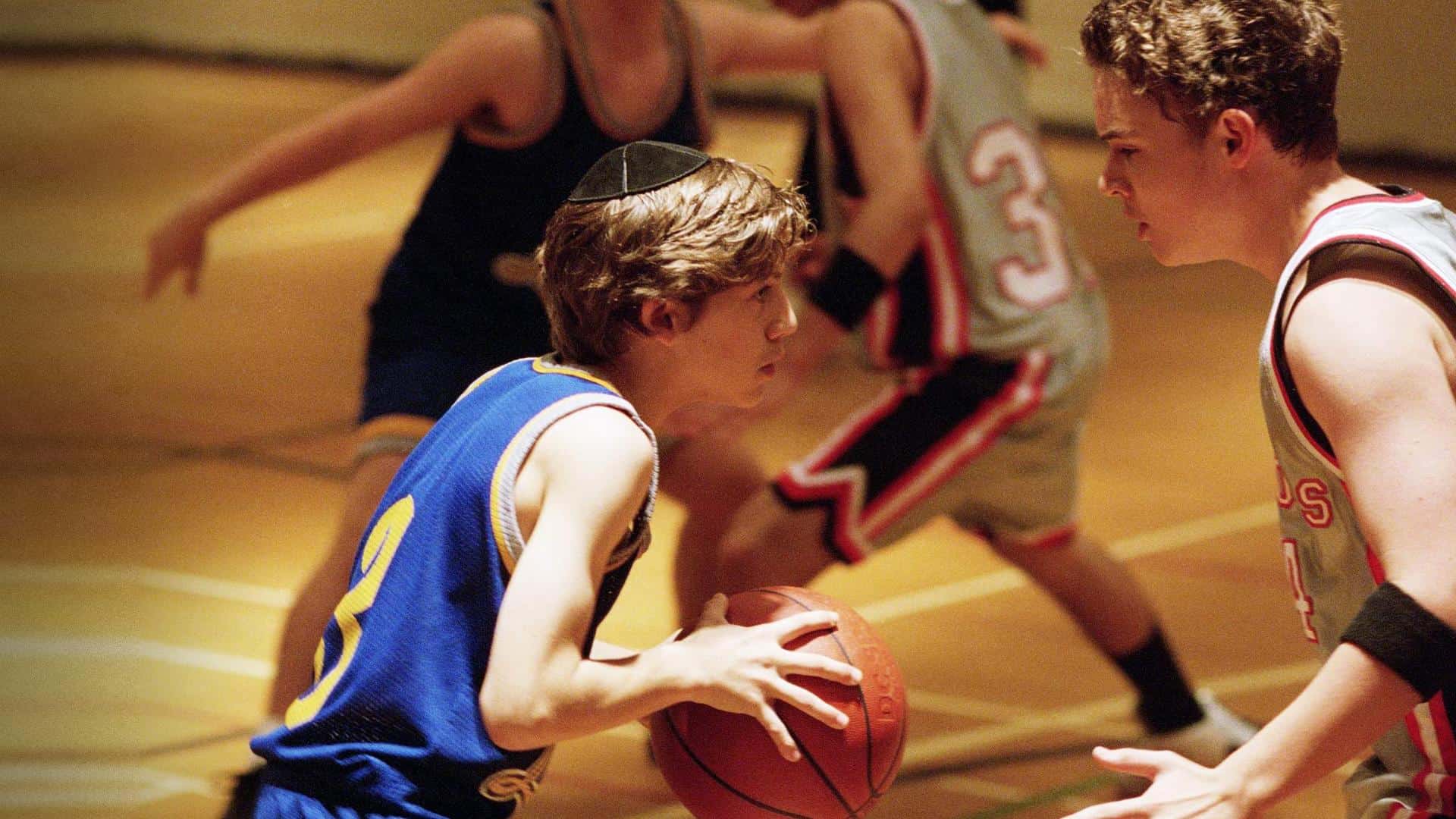 A teen plays basketball while wearing a kippah in this photo from Daniel L. Paulson Productions.