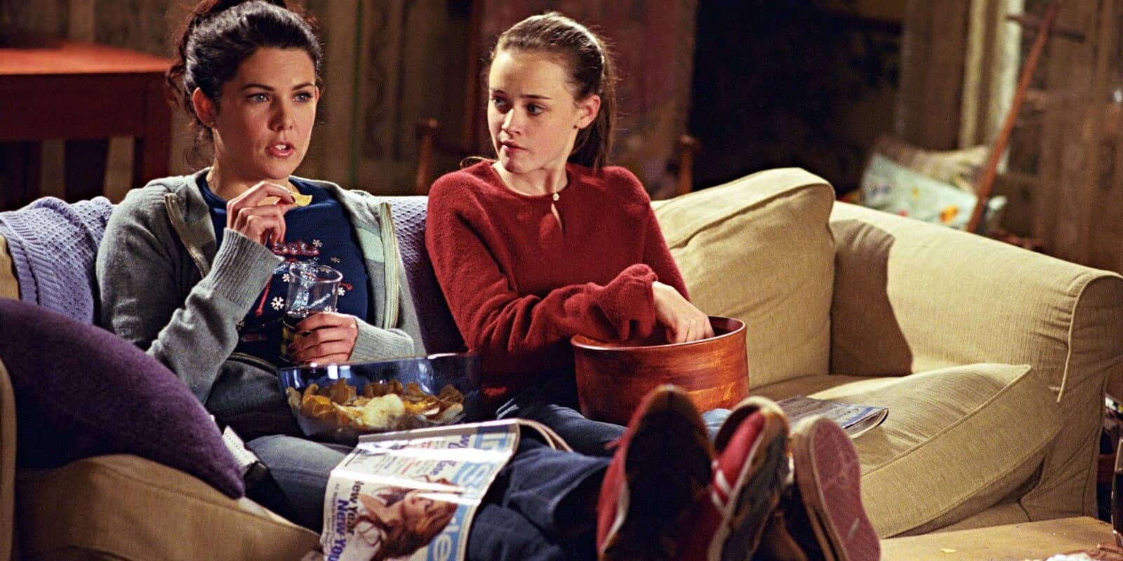 A mother and daughter watch a movie with a myriad of snacks in this image from Warner Bros. Television.
