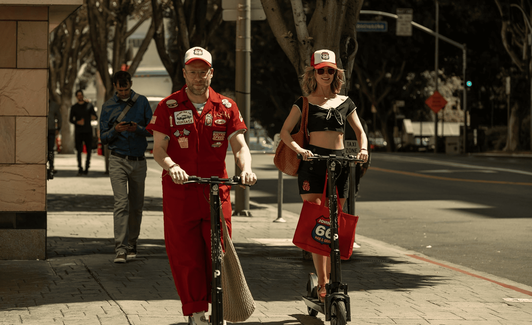 A woman and a man ride scooters in this image from Sony Pictures Television. 