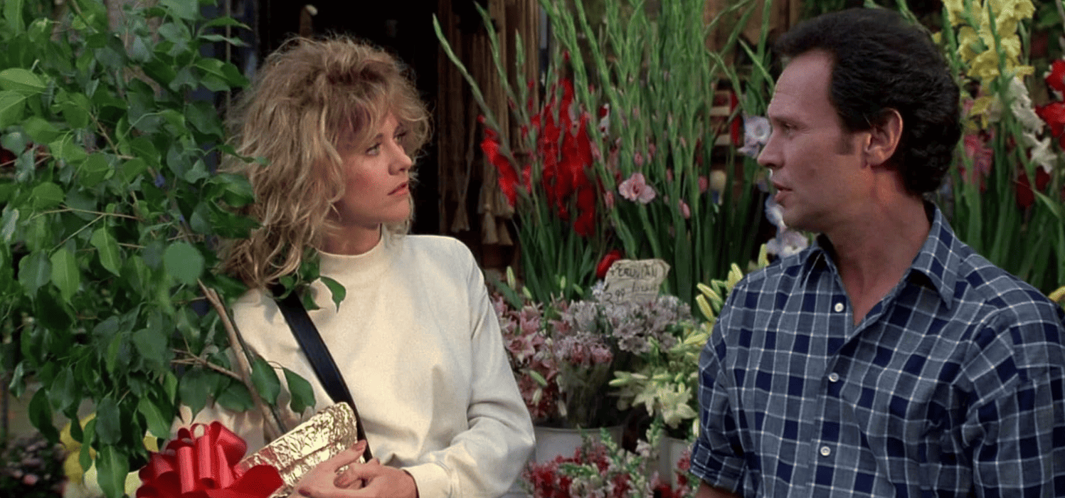 A woman and a man chat among flowers and plants in this image from Castle Rock Entertainment.