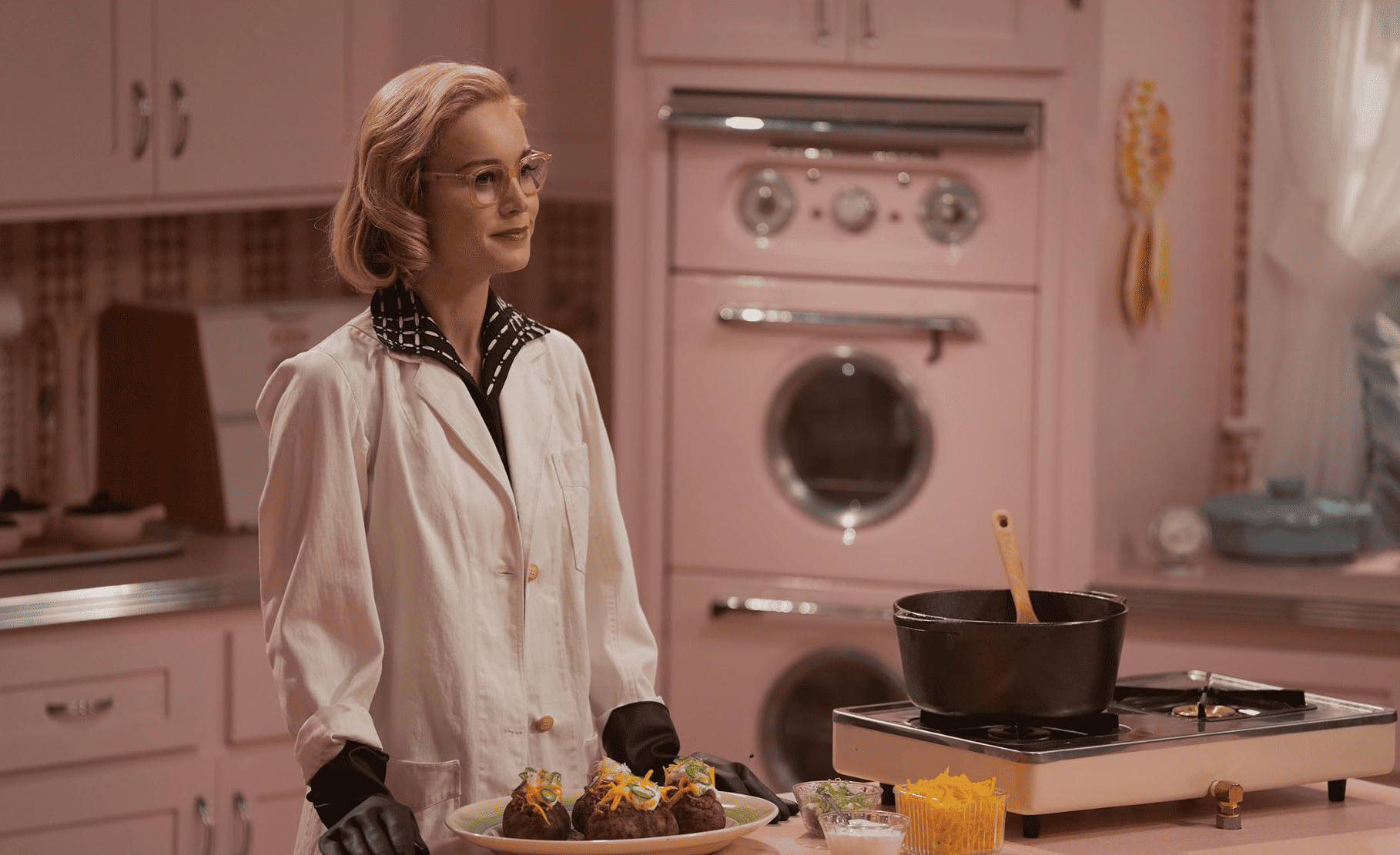 A woman in a lab coat makes dinner in this image from The Great Unknown Productions.