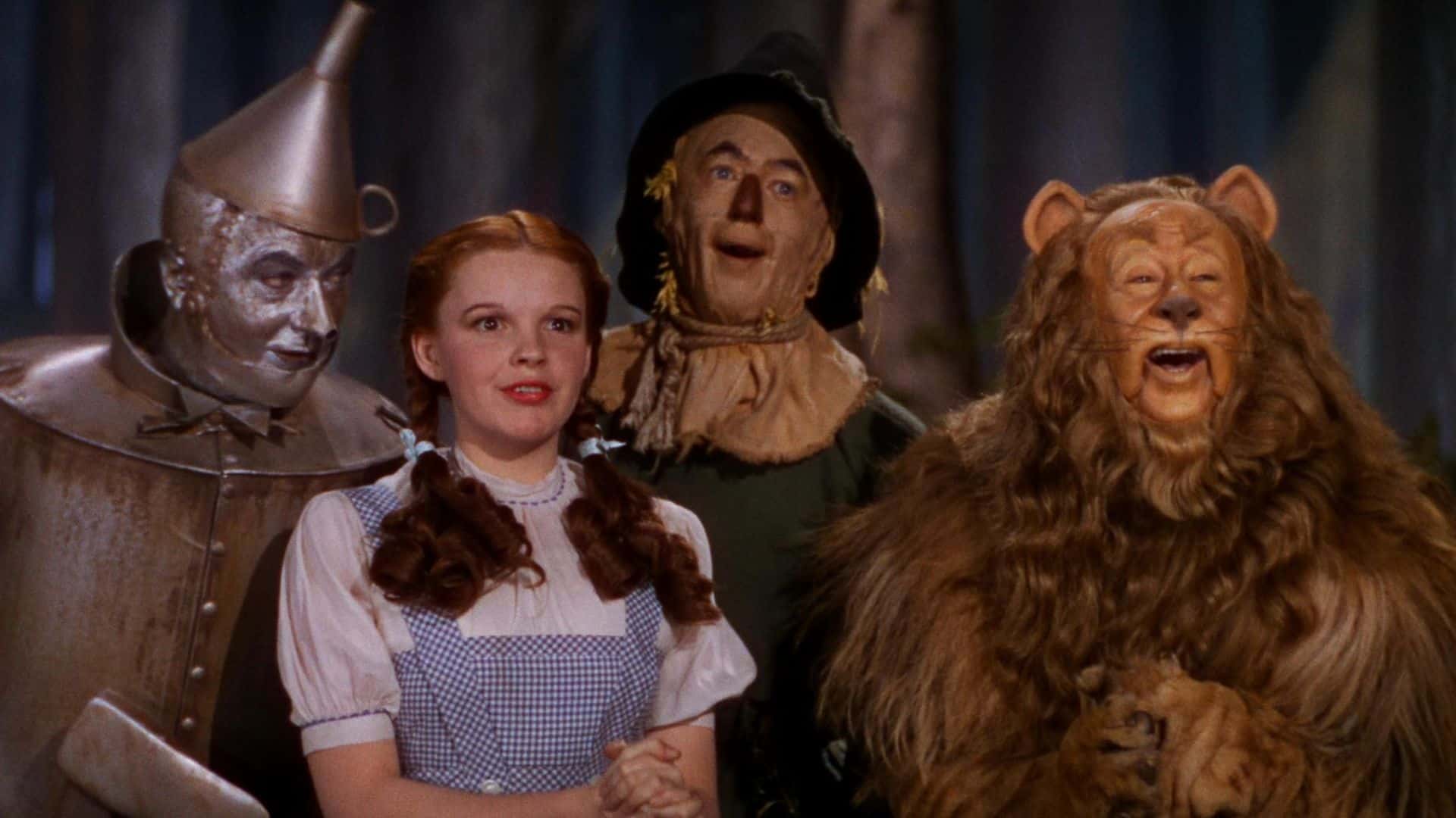 A tin man, a young girl, a scarecrow, and a lion smiling in this image from Metro-Goldwyn-Mayer.