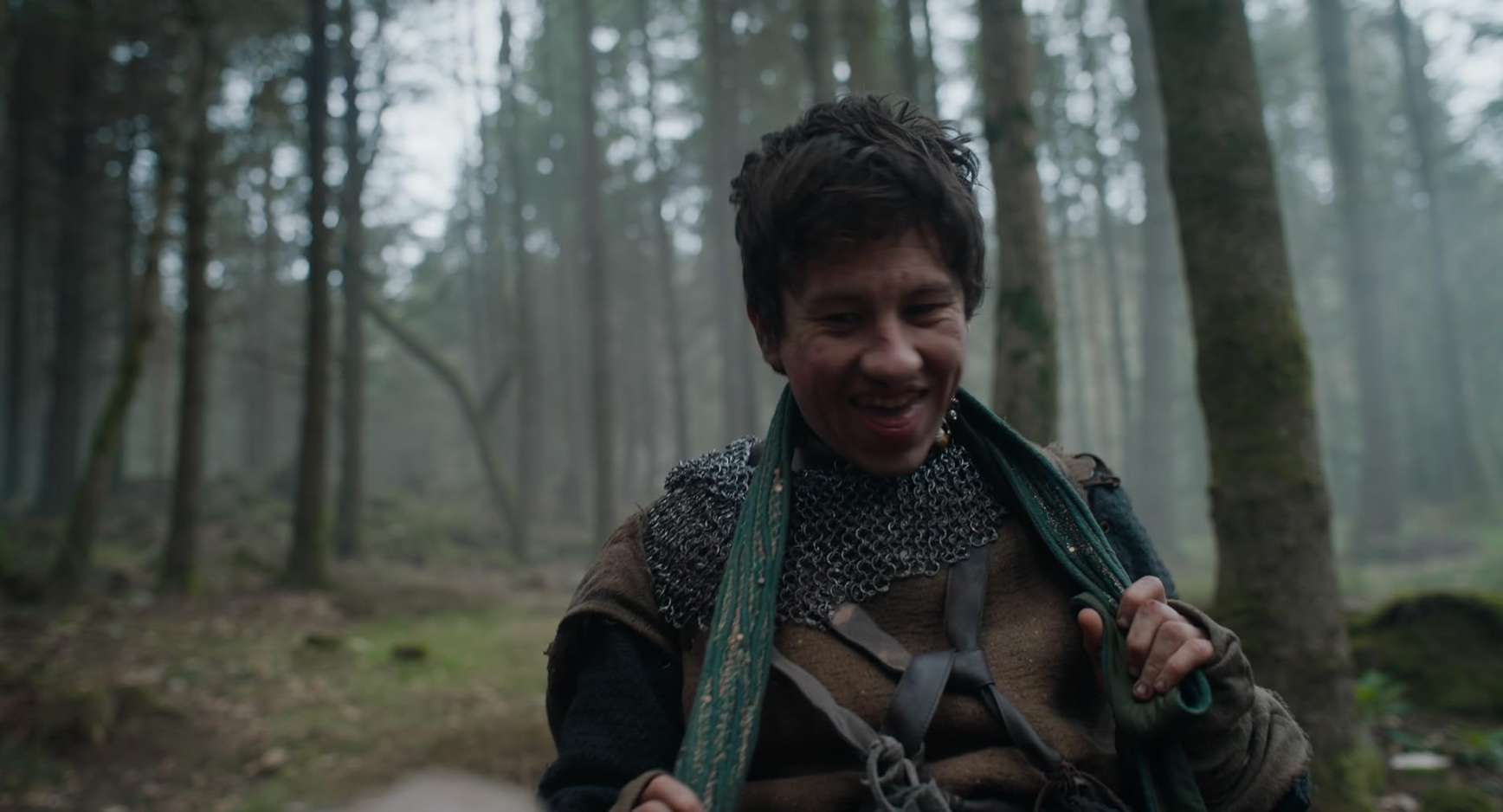 A man in chainmail sneers in the woods in this image from A24.