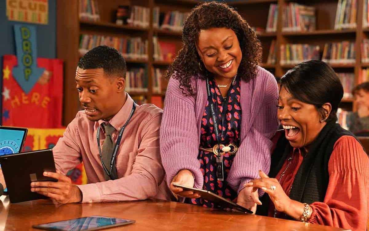 Three teachers laugh at pictures in a library in this image from Warner Bros. Television.