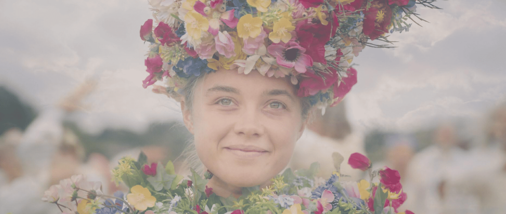A woman adorned in flowers smiles in this image from A24.