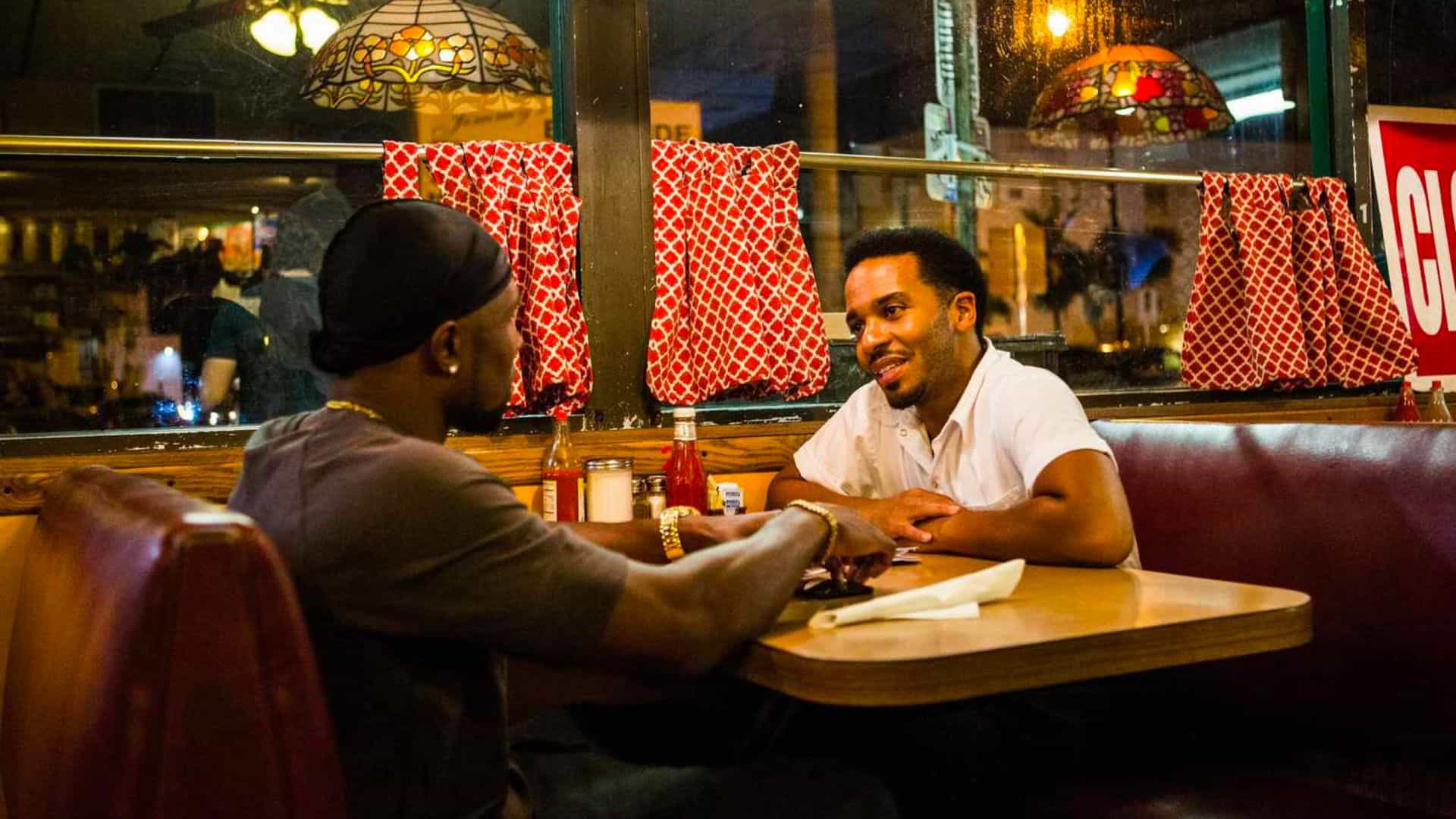 Two men sit in a diner booth at night in this image from A24.
