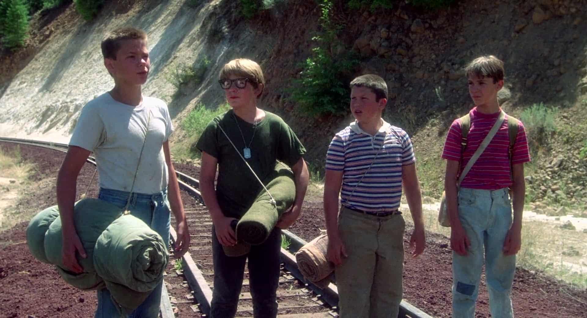 Four boys walk along a railroad track with packs in this image from Columbia Pictures.