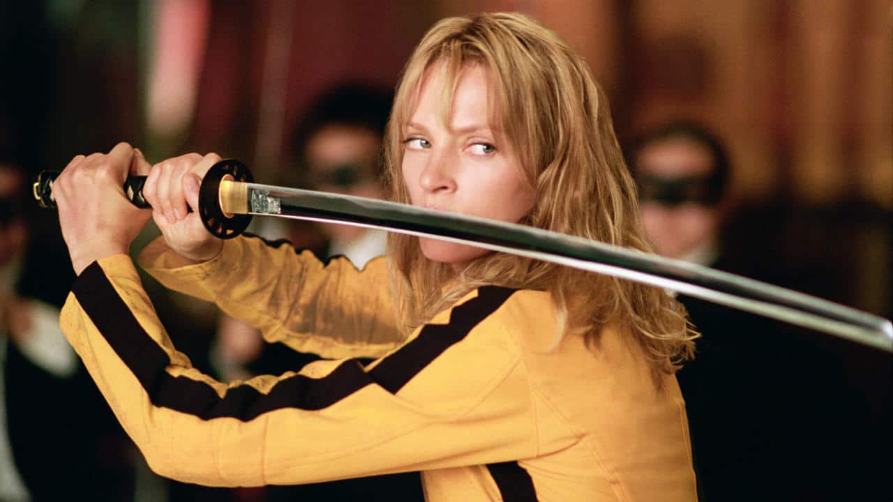 A woman in a yellow jumpsuit wields a samurai sword in this image from A Band Apart.