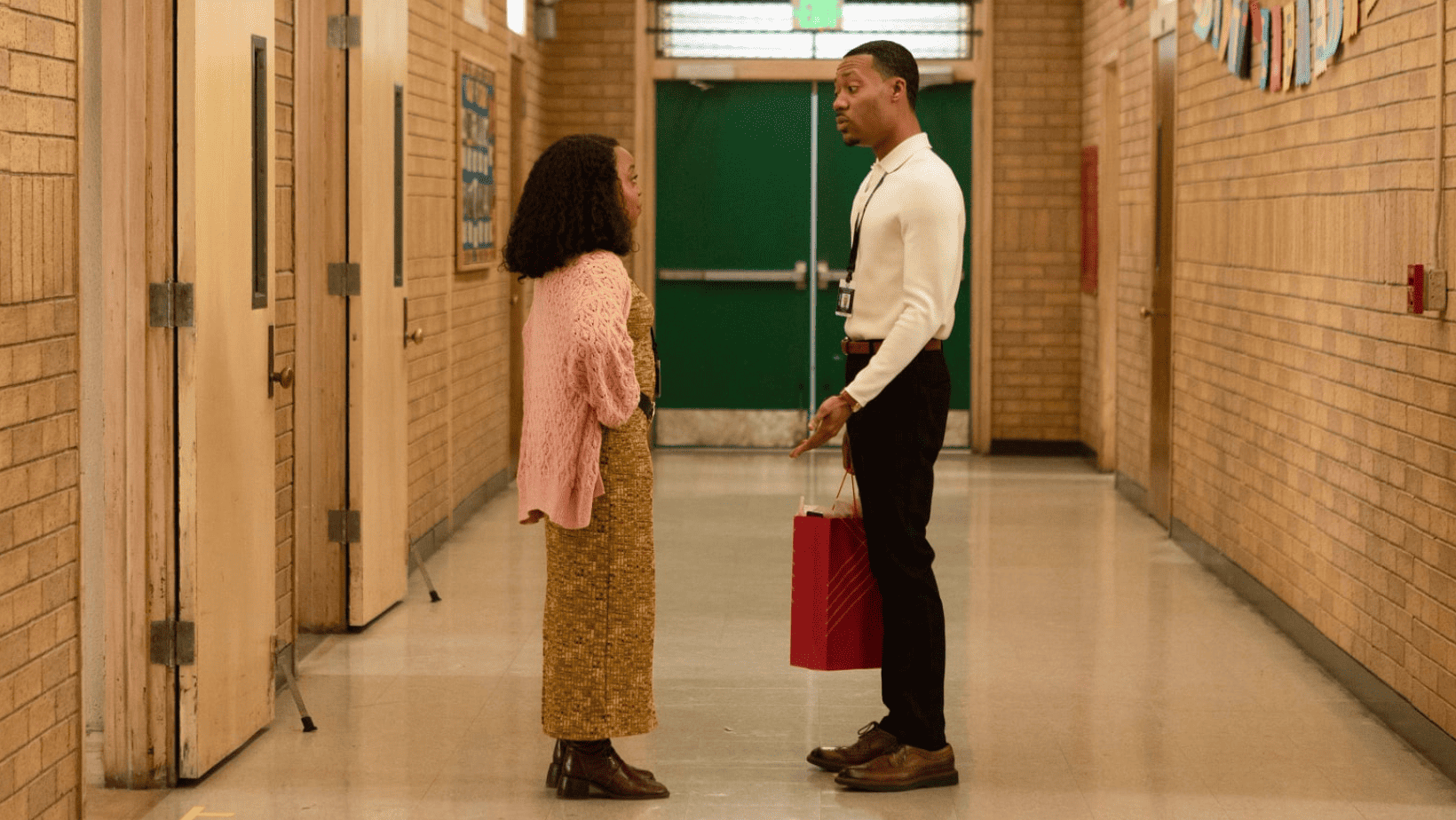 A couple stands facing each other in a school corridor in this image from Warner Bros. Television.