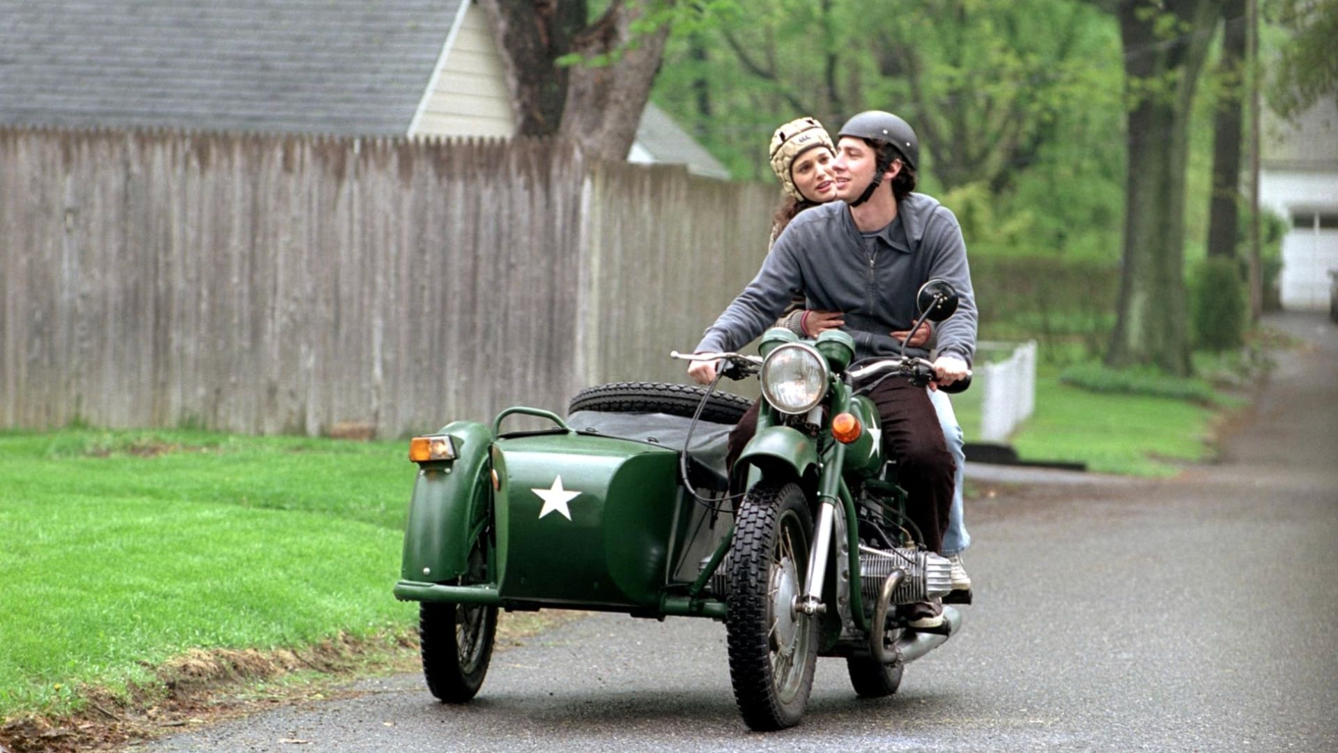A man and woman riding on an old green motorbike in this image from Camelot Pictures
