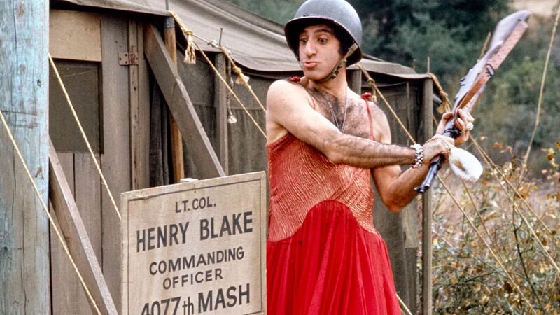 A soldier wearing a helmet and a red gown prepares to hit a sign with a rifle in this image from 20th Century Fox Television.