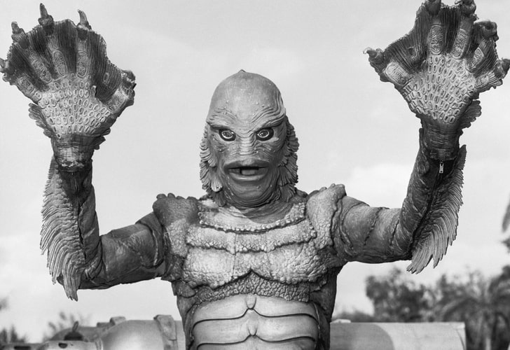 An amphibious-looking man-creature raises his arms in this image from Universal-International.