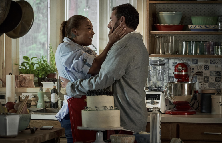 A couple happily embraces in their kitchen in this image from Happy Madison Productions.