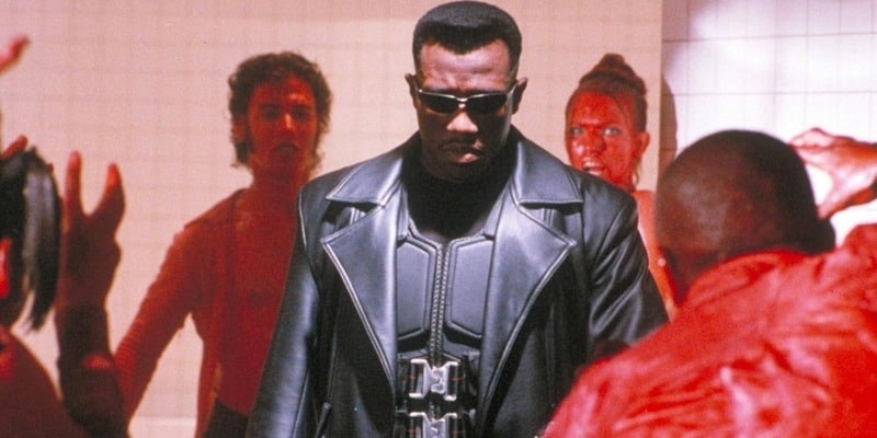 A man in black body armor stands in a crowd threatening him in this image from New Line Cinema.