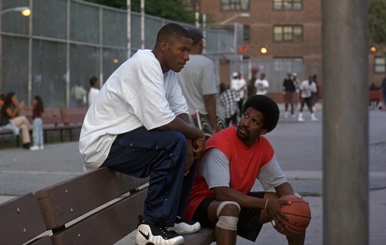 Two men sit on a bench at a basketball court in this image from Touchstone Pictures.