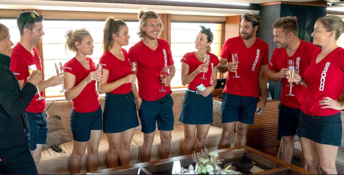 A group of young people in matching uniforms hold champagne glasses in this image from 51 Minds Entertainment.