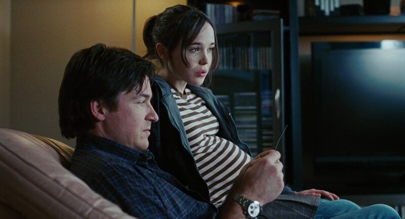 A man and a teenage girl sit on the couch together in this photo from Mandate Pictures.
