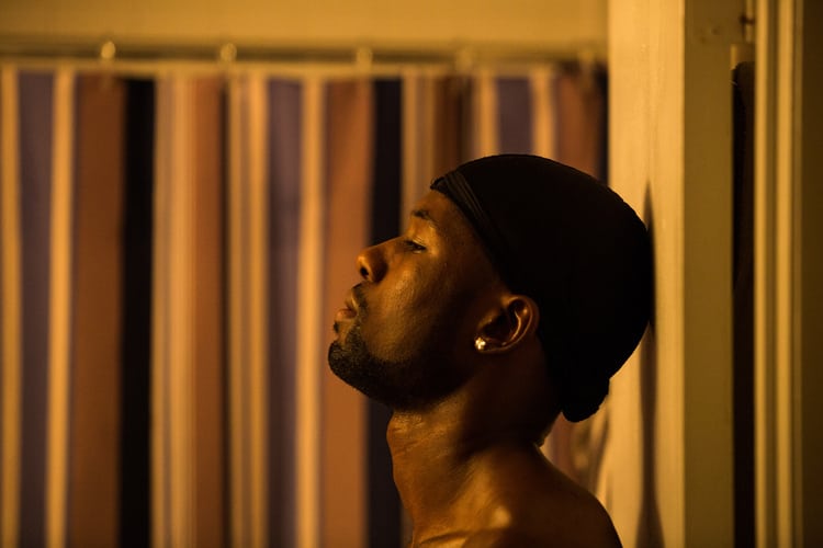 A man in a durag leans against a motel wall in this photo from A24.