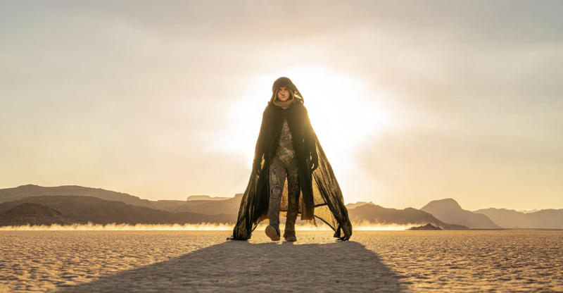 A man wearing a cloak walks toward the camera with the sun behind him in this image from Legendary Pictures.