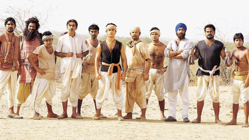 A group of men, dressed in traditional attire, stand determined in a barren landscape, ready for a challenge, in this image from Aamir Khan Productions.