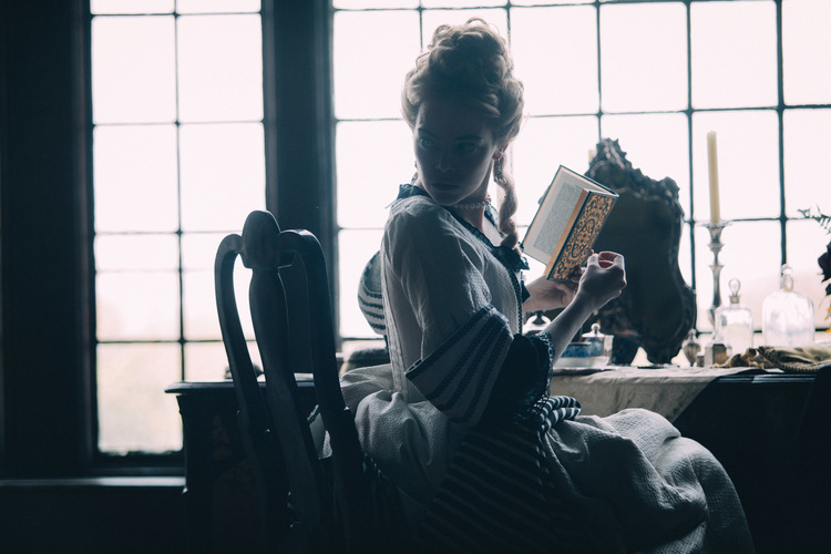A woman in period dress reading a book in this image from Scarlet Films.