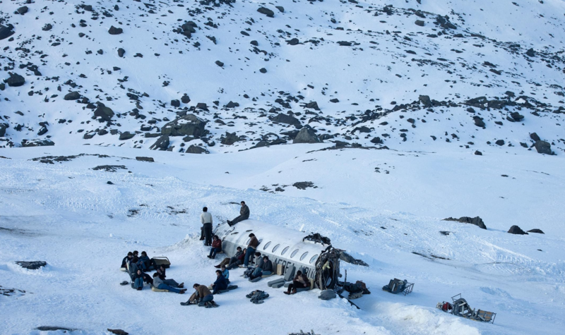 A group of people sit beside a downed aircraft in this image from Misión de Audaces Films.