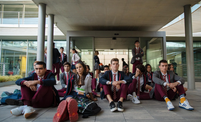 A group of students sits outside a building in this image from Zeta Producciones.
