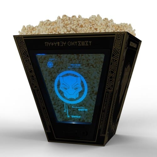 A black, four-sided bucket with two clear panels filled with popcorn in this image from AMC.
