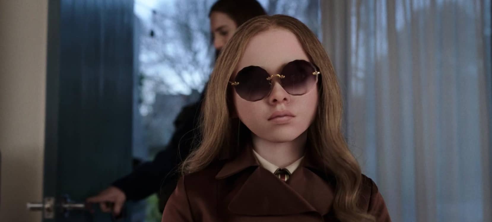 A doll stands in a doorway wearing sunglasses in this image from Universal Pictures.