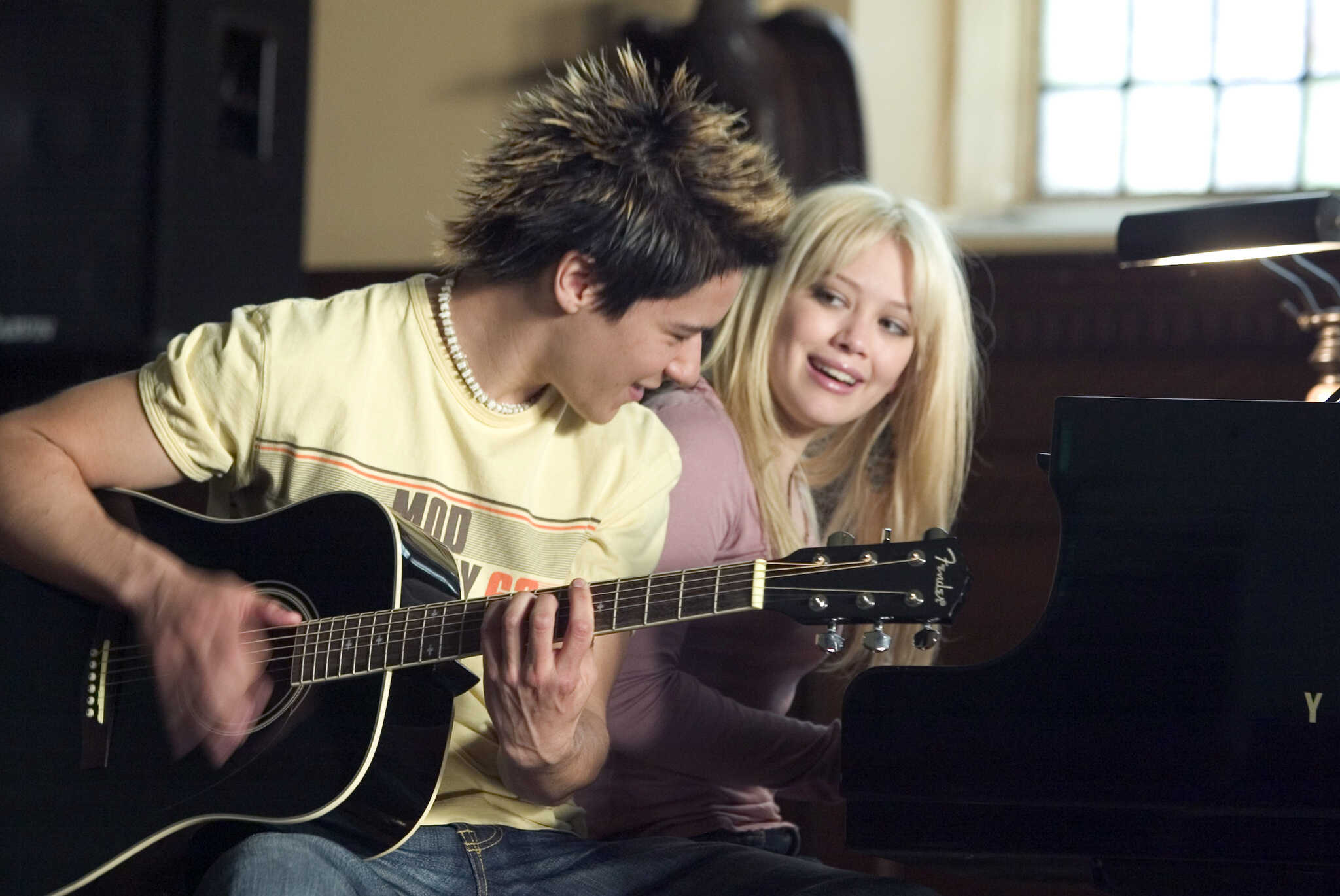A boy plays guitar while a girl plays piano in this image from New Line Cinema.