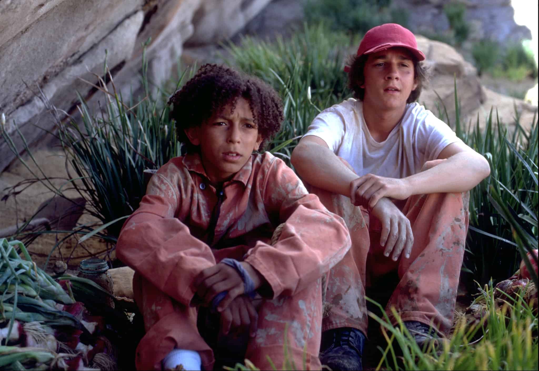 Boys in jumpsuits sit in the grass in this image from Walt Disney Pictures.