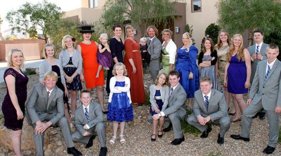 A group in formal clothes poses in front of a house in this image from Figure 8 Films.