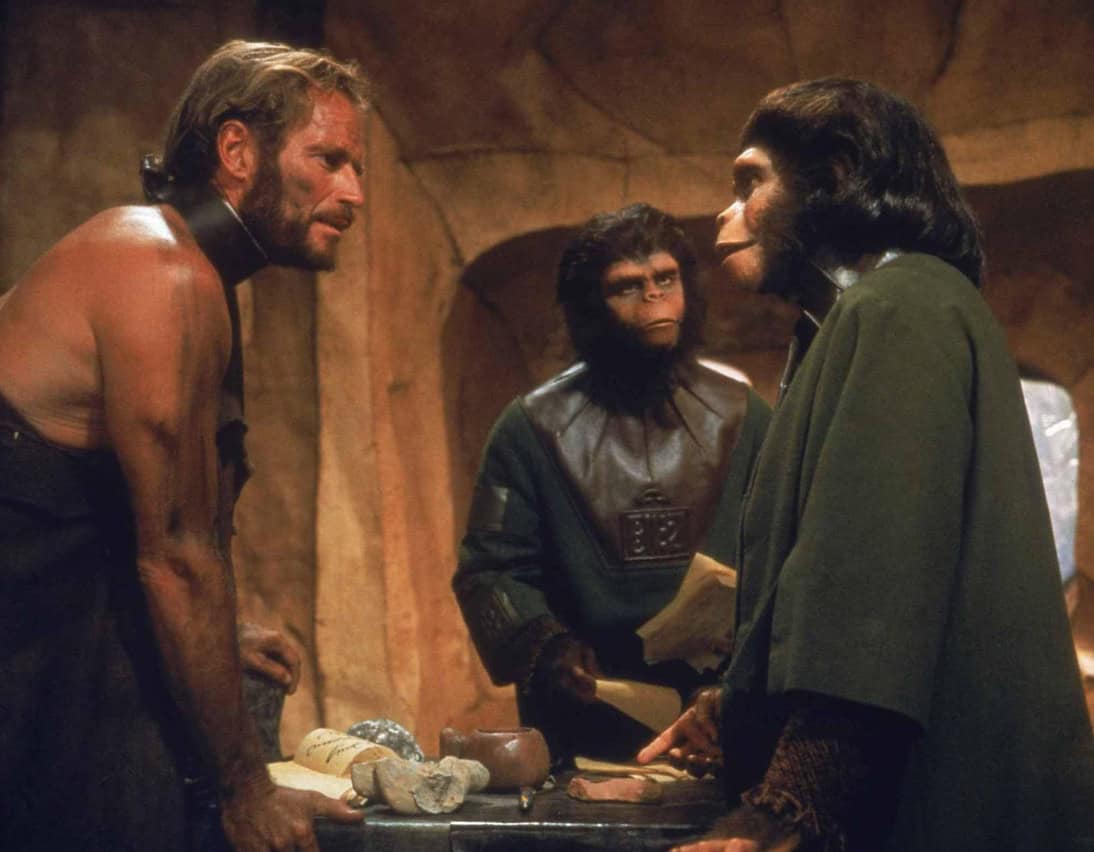 A captive man speaks with two apes in this image from APJAC Productions.